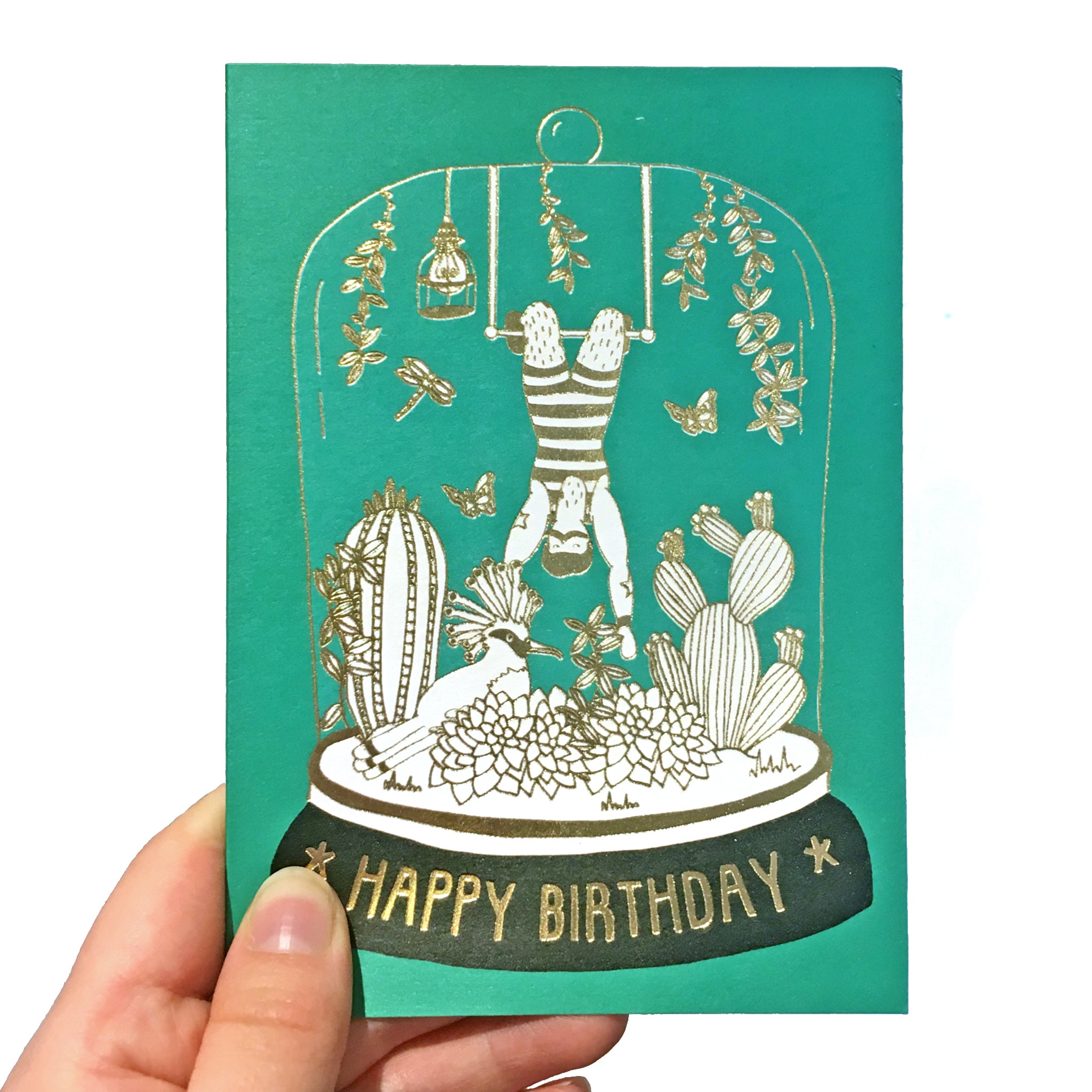 Green birthday card with gold detail featuring an acrobat in a belljar
