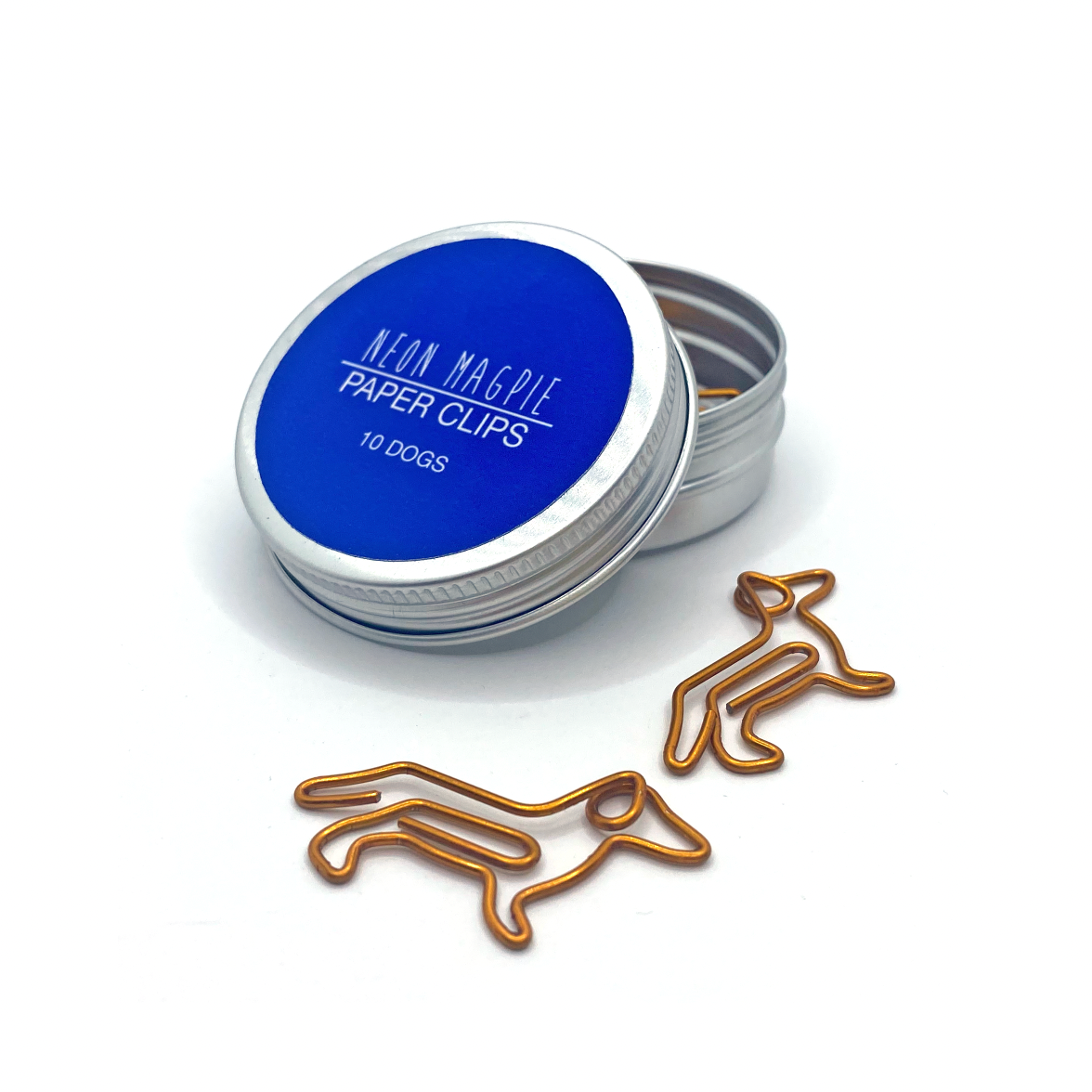 Copper coloured dog shaped paper clips in a silver tin